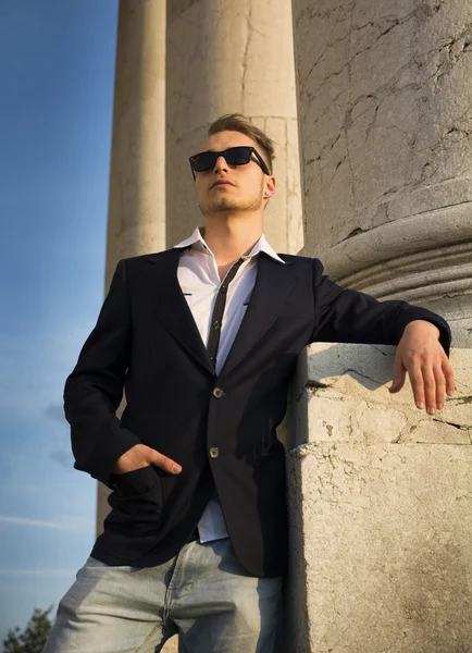 Handsome blond young man with marble columns behind him — Stok Foto