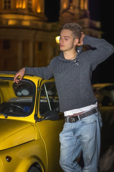 Tir de nuit du jeune homme, debout à côté de la petite voiture — Photo