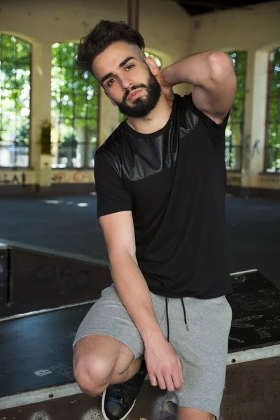 yakışıklı bir genç adam sakallı, t-shirt ve şort giyiyor