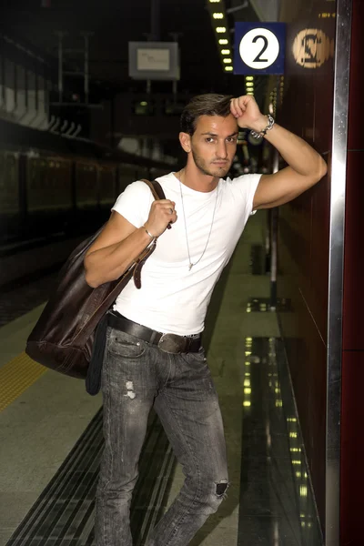 기차 또는 지하철 역의 벽에 서 있는 잘생긴 젊은 남자 — 스톡 사진