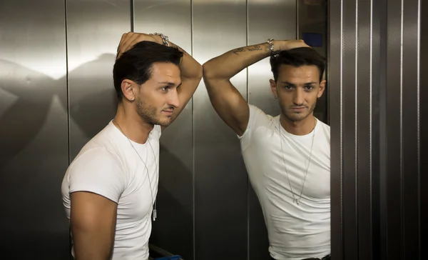 Joven guapo apoyada contra el espejo dentro de un elevador (ascensor) — Foto de Stock