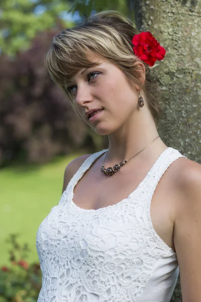 Mulher jovem e atraente com uma rosa vermelha no cabelo — Fotografia de Stock