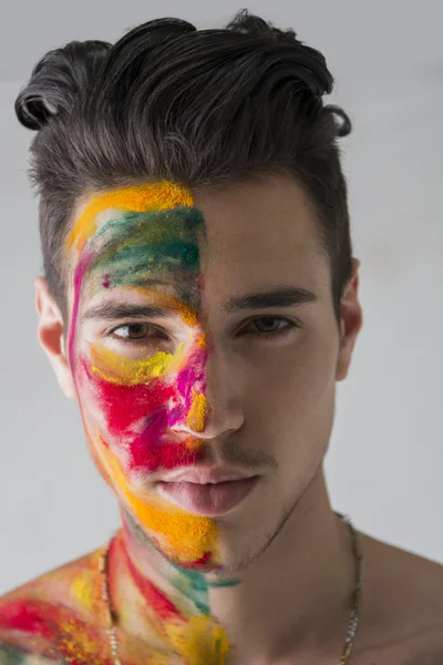 Head-shot of attractive young man, skin painted with Holi colors