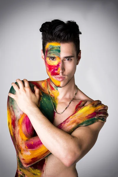 Attractive young man shirtless, skin painted all over with colors