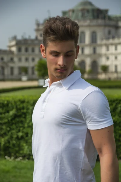 Joven apuesto al aire libre, antiguo Palacio Real elegante detrás de él —  Fotos de Stock