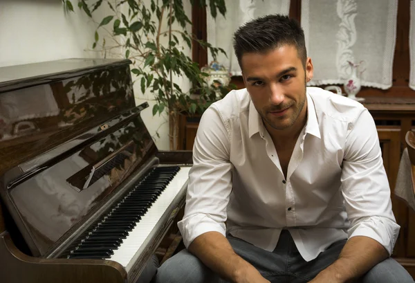 Male artist sitting next to his upright piano — Stock Photo, Image