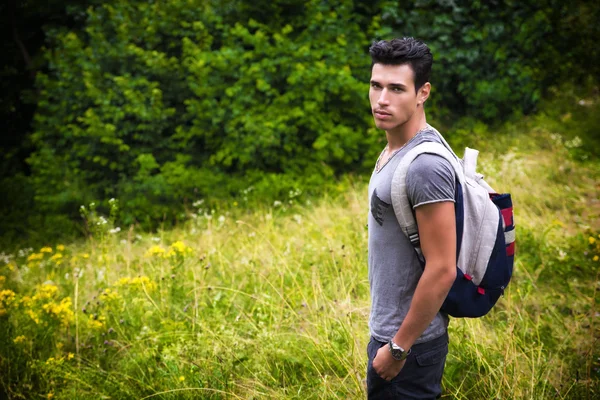 Handsome athletic young man with backpack in mountains — Stock Photo, Image