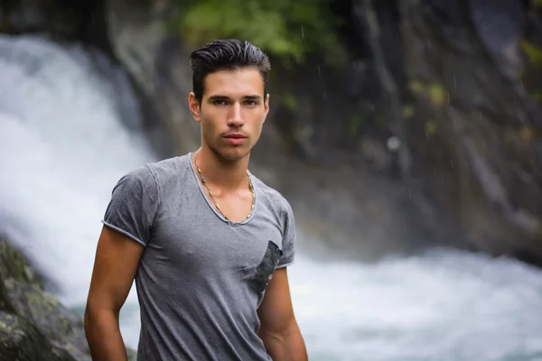 Handsome young man near mountain waterfall — Stock Photo, Image