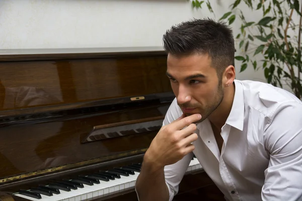 Artista masculino sentado ao lado do piano — Fotografia de Stock