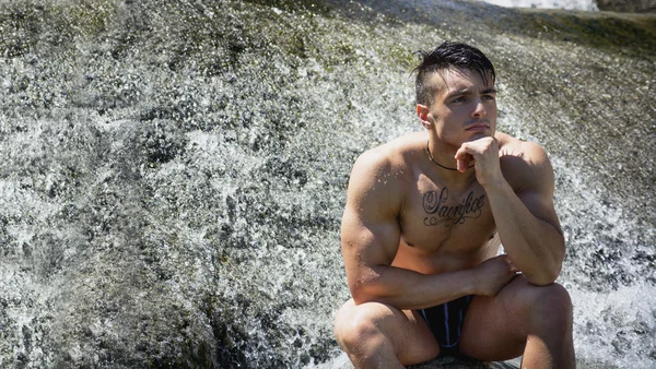 Man wearing a swimsuit near waterfall or river water — Stock Photo, Image