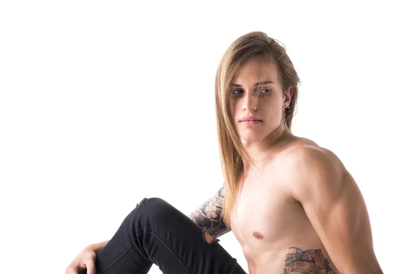 Uomo dai capelli lunghi con tatuaggi seduto — Foto Stock
