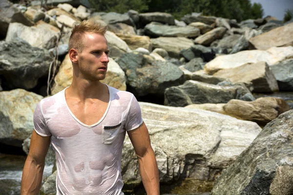 Bodybuilder am Meer mit nassen T-shirt auf — Stockfoto
