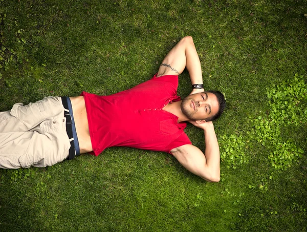 Passen mannelijk model liggen op het gras — Stockfoto