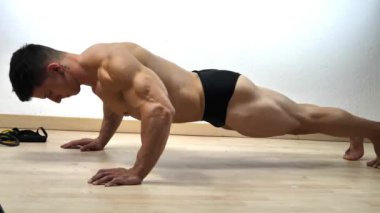 Spor salonunda yerde şınav çeken genç bir adam.