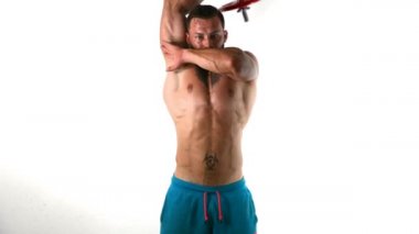 Kaslı, seksi, üstsüz, dambılı kol kasları çalıştıran, stüdyoda beyaz tenli bir adam.