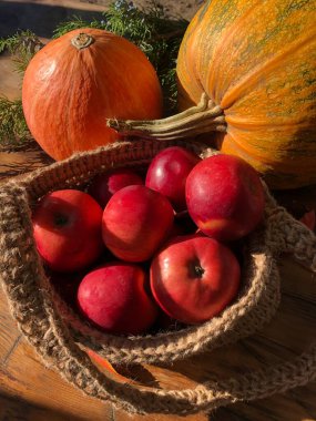 Balkabağı, elma ve çiçekler masada.