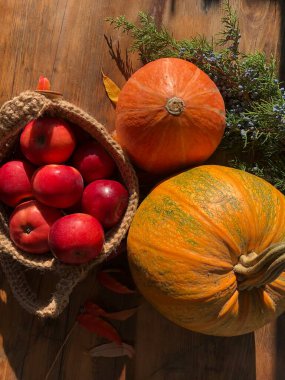 Balkabağı, elma ve çiçekler masada.
