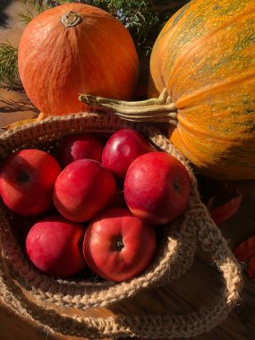 Balkabağı, elma ve çiçekler masada.