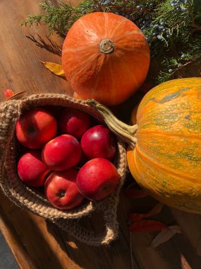 Balkabağı, elma ve çiçekler masada.