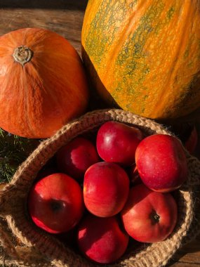 Balkabağı, elma ve çiçekler masada.
