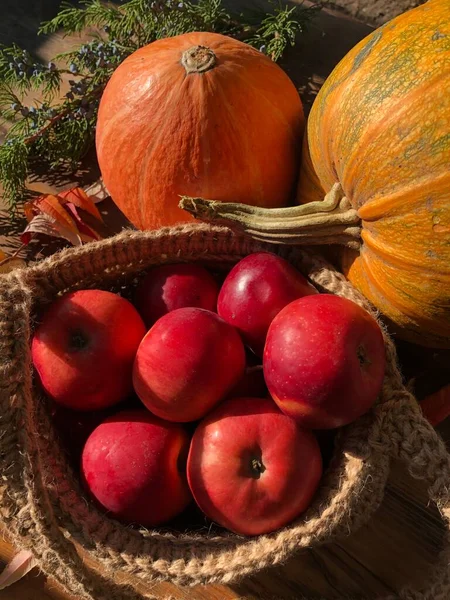 Balkabağı, elma ve çiçekler masada.