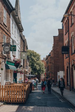 York, İngiltere - 22 Haziran 2021: Antik Romalılar tarafından kurulmuş, kuzeydoğu İngiltere 'de duvarlarla çevrili bir şehir olan York' taki bir sokakta, restoranların ve kafelerin önünden geçen insanlar.
