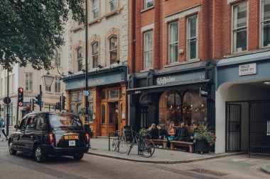 Londra, İngiltere - 09 Ekim 2021: Fitzrovia 'daki Kafe Kafe' nin dışındaki insanlar, Londra 'nın çeşitli bölgelerinde restoranlar, oteller, galeriler ve eski moda barlar, taksi geçişleri.