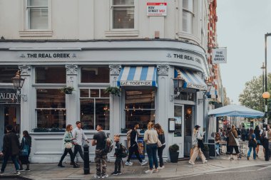 Londra, İngiltere - 09 Ekim 2021: Covent Garden 'da bir caddedeki The Real Greek restoranı, Londra' da bir sürü dükkan ve lokantası olan ünlü bir turistik bölge, insanlar dışarıda..