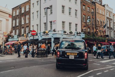 Londra, İngiltere - 09 Ekim 2021: Covent Garden 'daki kafelerin ve restoranların önündeki modern siyah taksi, Londra' da bir çok mağazası ve restoranı olan ünlü bir turistik bölge..