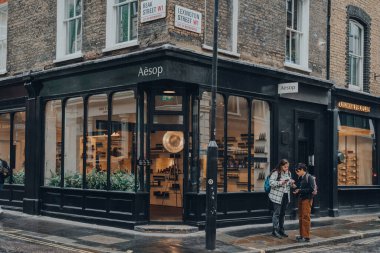 Londra, İngiltere - Ekim 02, 2021: Covent Garden 'daki Ezop mağazası, Londra' da bir çok mağazası ve restoranı olan popüler bir turizm alanı, kadınlar cep telefonlarının önünde yönlerini arıyorlar.
