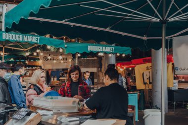 Londra, İngiltere - 17 Ekim 2021: Borough Market 'teki bir simit dükkanında satıcı ve müşteriler, Londra' nın en büyük ve en eski gıda pazarlarından biri, seçici odaklı.
