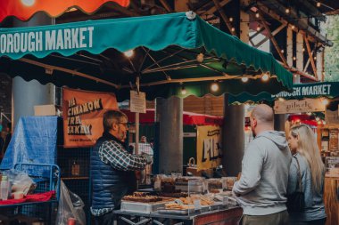 Londra, İngiltere - 17 Ekim 2021: Londra 'nın en büyük ve en eski gıda pazarlarından biri olan Borough Market' teki Tarçın Ağacı Pastanesi 'nde satıcı ve müşteri.