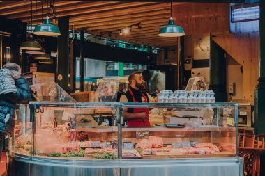 Londra, İngiltere - 17 Ekim 2021: Londra 'nın en büyük ve en eski gıda pazarlarından biri olan Borough Market' teki taze et ve kümes hayvanları standında çalışan adam.