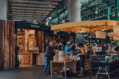 Londra, İngiltere - 17 Ekim 2021: Londra 'nın en büyük ve en eski gıda pazarlarından biri olan Borough Market' teki peynir standındaki insanlar.