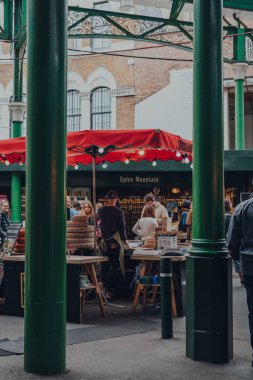 Londra, İngiltere - 17 Ekim 2021: Londra 'nın en büyük ve en eski gıda pazarlarından biri olan Borough Market' teki peynir tezgahındaki insanların sütunlarından bakın.