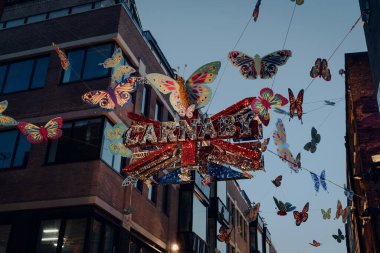 Londra, İngiltere - 23 Kasım 2021: Carnaby Caddesi 'ndeki Kelebeklerle çevrili Shimmering Carnaby tabelasının yan görüntüsü.