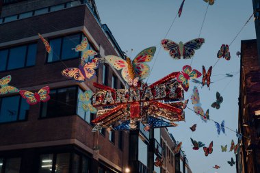 Londra, İngiltere - 23 Kasım 2021: Carnaby Caddesi 'ndeki Kelebeklerle çevrili Shimmering Carnaby tabelasının yan görüntüsü.