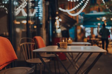 Kışın bir restoranın açık hava masasında mum yakmak, arka planda Noel ışıkları, seçici odak, bokeh.
