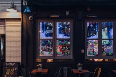 London, UK - November 23, 2021: Merry Christmas sign on the window of O'Neills pub in Soho, an area of London with lots of cafes and restaurants.