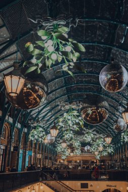 London, UK - November 23, 2021: Christmas decorations, mistletoe and giant festive baubles in Covent Garden Market, one of the most popular tourist sites in London, UK.
