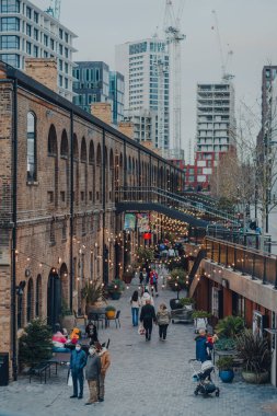 Londra, İngiltere - 01 Ocak 2022: Coal Drops Yard 'da ışıkların altında yürüyen insanlar, King' s Cross St Pancras istasyonları yakınlarındaki bir alışveriş merkezi ve yemek merkezi 2018 yılında açıldı..