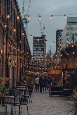 Londra, İngiltere - 01 Ocak 2022: Coal Drops Yard 'da ışıkların altında yürüyen insanlar, King' s Cross St Pancras istasyonları yakınlarındaki bir alışveriş merkezi ve yemek merkezi 2018 yılında açıldı..