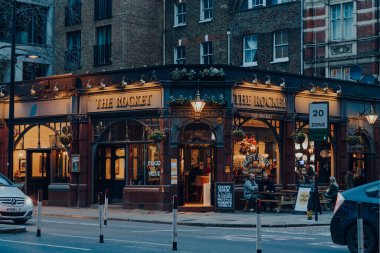 London, UK - January 01, 2022: View of The Rocket pub, one of the busiest pubs in Euston and King's Cross, London, people and cars on the road in front.