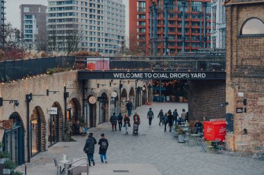 Londra, İngiltere - 01 Ocak 2022: Coal Drops Yard 'da karşılama tabelası altında yürüyen insanların yüksek açılı görüntüsü, King' s Cross istasyonu yakınlarında bir alışveriş merkezi ve yemek merkezi 2018 yılında açıldı..