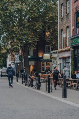 Londra, İngiltere - 23 Ekim 2021: Exmouth Market, Clerkenwell, Islington 'da yarı yayalara ayrılmış bir cadde ve ünlü bir sokak pazarında parketmiş bisikletler. İnsanlar geçip gidiyor, şehir hayatı konsepti.