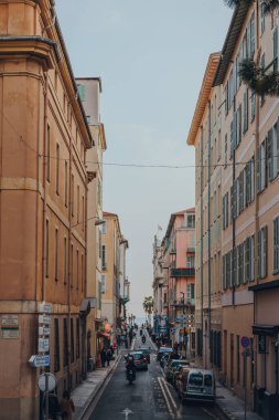 Nice, Fransa - 10 Mart 2022: Fransız Rivierası 'nda ünlü bir turizm merkezi olan Nice' te geleneksel pastel renkli binalarla kaplı tipik dar bir cadde manzarası.