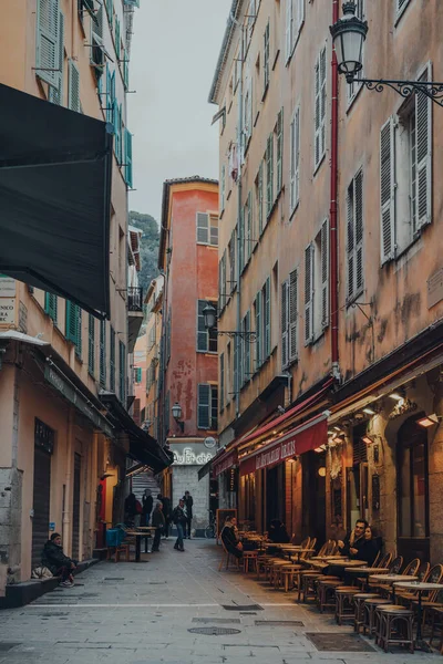 Nice, Fransa - 10 Mart 2022: Eski Nice Kasabası 'nda dar bir sokakta barlar ve restoranlar, Fransız Rivierası' nda ünlü bir turizm merkezi, dışarıda insanlar.