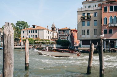 Venedik, İtalya - 21 Mayıs 2022: Venedik 'in başkenti Venedik' teki Büyük Kanal 'da ilerleyen bir su taksisinin ahşap direklerinden ve ünlü bir seyahat noktası, seçici bir odak noktası.