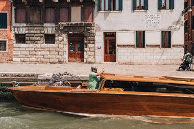 Venedik, İtalya - 22 Mayıs 2022 Venedik 'te bir kanalda müşteri bekleyen özel taksi şoförü. Şehirdeki ana ulaşım aracı teknelerdir..