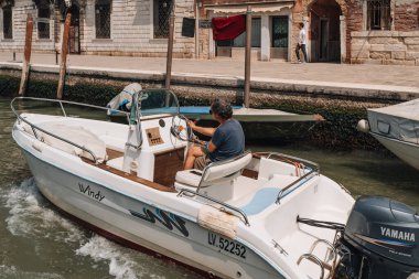 Venedik, İtalya - 22 Mayıs 2022: Venedik 'te dar bir kanalda yulaf süren bir adamın yüksek açılı görüntüsü. Şehirdeki ana ulaşım aracı teknelerdir..
